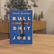 Blue cover book "Bullshit jobs" standing upright on a wooden table.